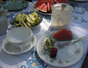 traditionell gedeckter Kaffeetisch mit Kiwis, Melone, Kirschen und Sahne