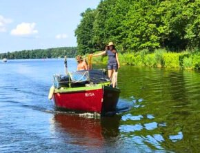 Frau mit Sonnenhut auf einem roten Kajütboot im Oder-Spree-Kanal