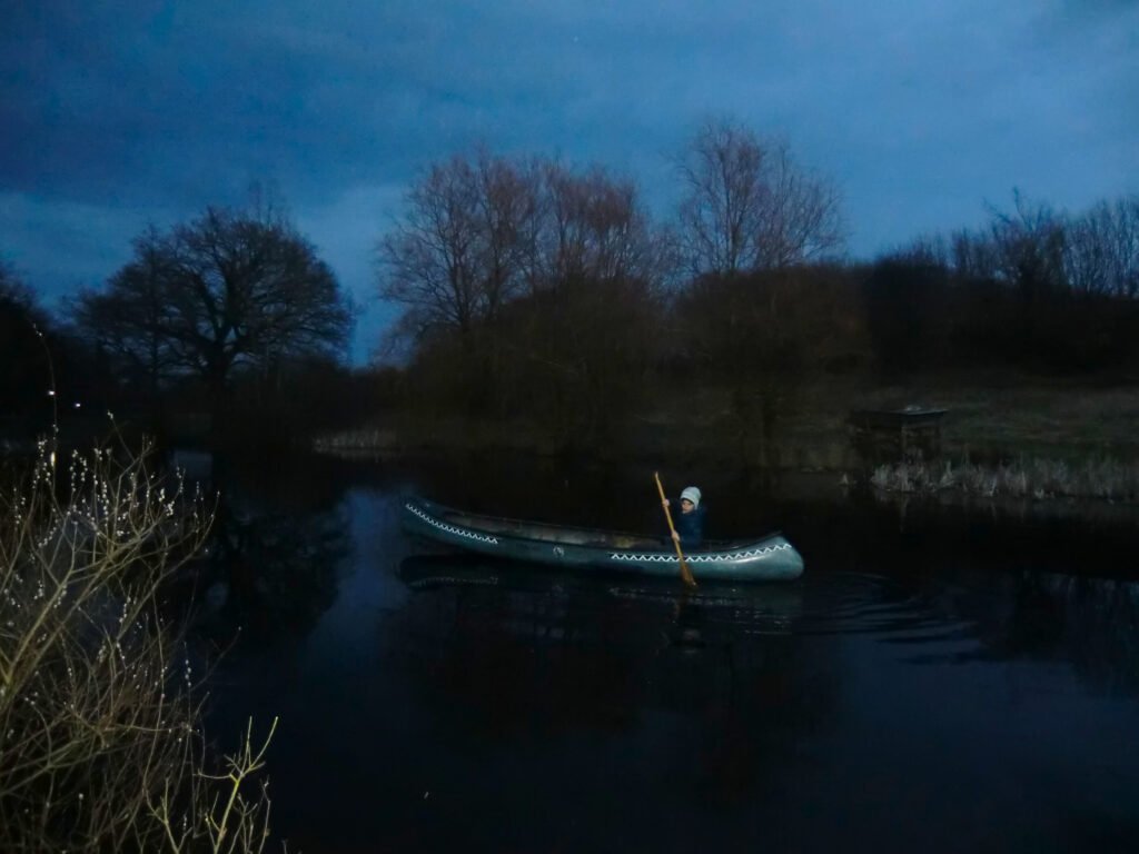 Junge im Kanu auf einem Teich bei Nacht in Westensee in Schleswig-Holstein