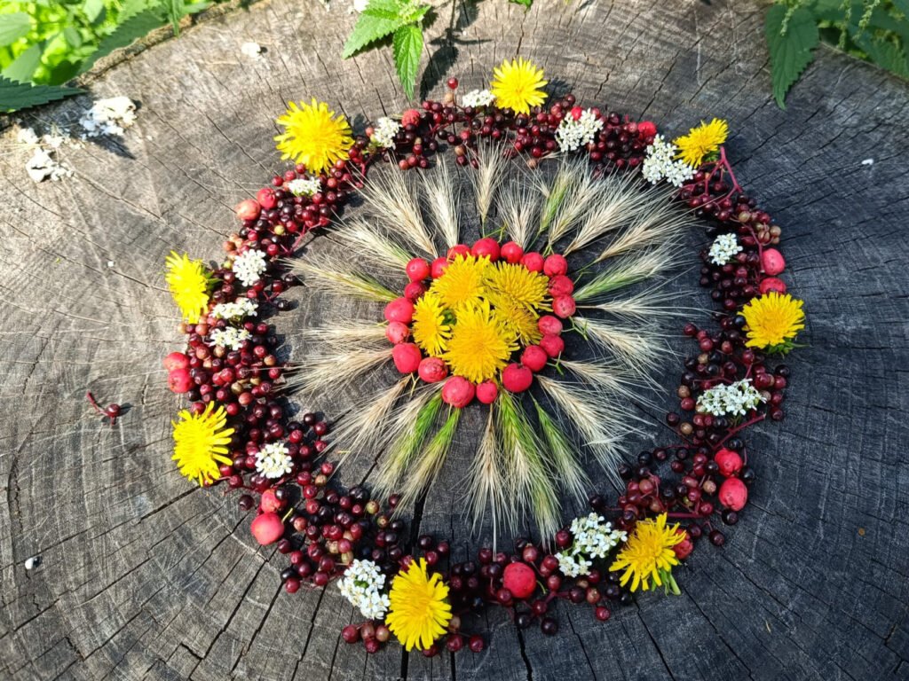 Mandala aus gelben und weißen Blüten, Ähren und roten Beeren auf einem Baumstamm